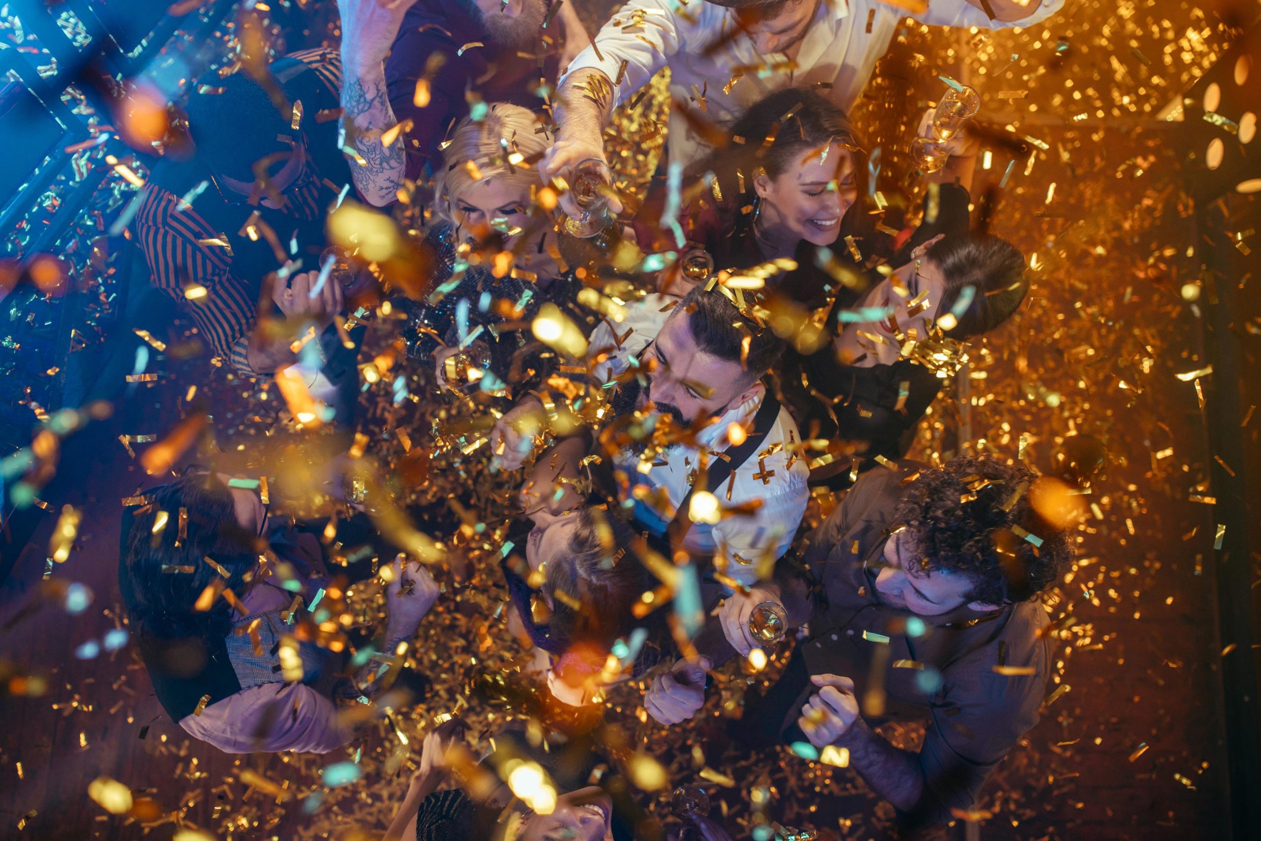 Grupo de jóvenes amigos bailando juntos en la discoteca, rodeados de confeti costa azahar
